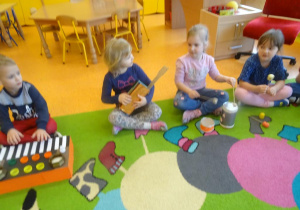 Czwórka dzieci gra na instrumentach muzycznych wykonanych wspólnie z rodzicami z materiałów pozyskanych z domowego recyklingu.